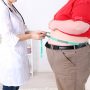 Doctor examining patient obesity on light background