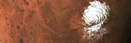 Aerial view of a white ice cap on the surface of Mars surrounded by reddish terrain and craters.