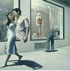 A couple walking together in front of a lingerie store window displaying mannequins and clothing.